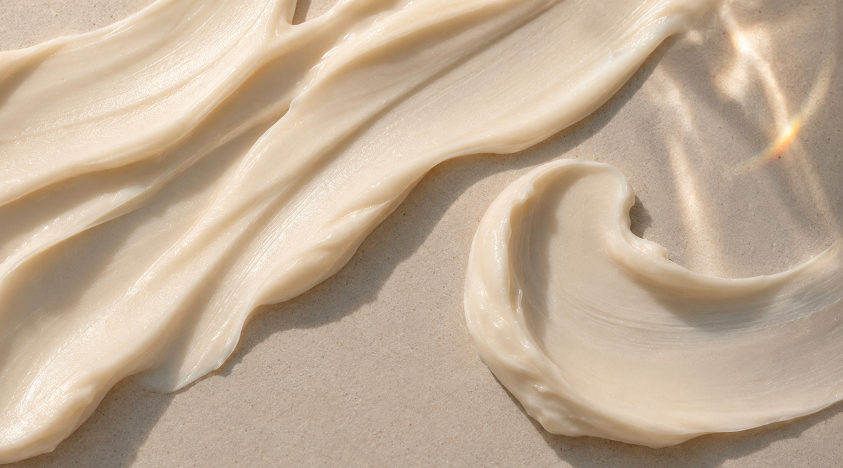 Close-up of a smooth cream texture spread across a warm neutral surface.