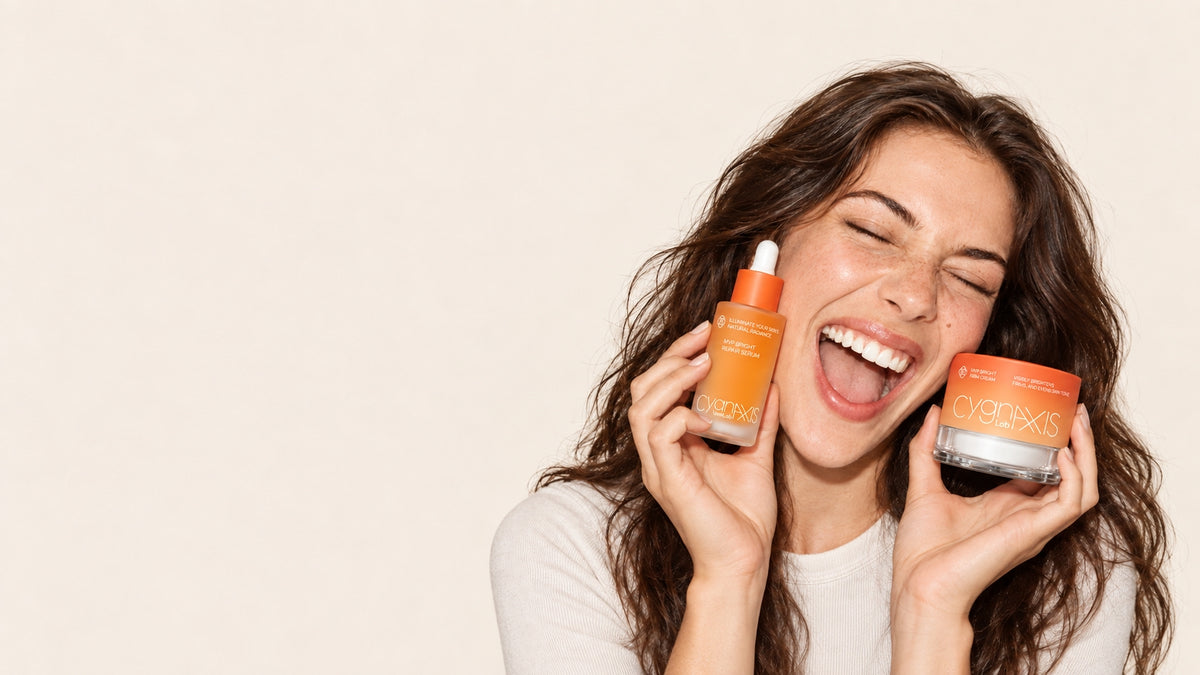 Woman holding CYGNAXIS Lab serum and face cream beside her face.