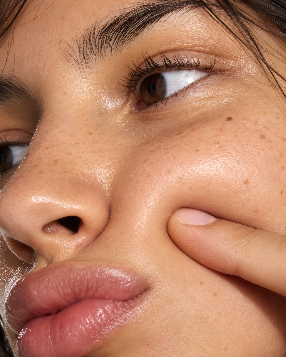 Close-up of a woman gently pressing her cheek with her fingers.